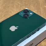 Green iPhone backside with dual camera module and Apple logo on a box, wooden surface in the background